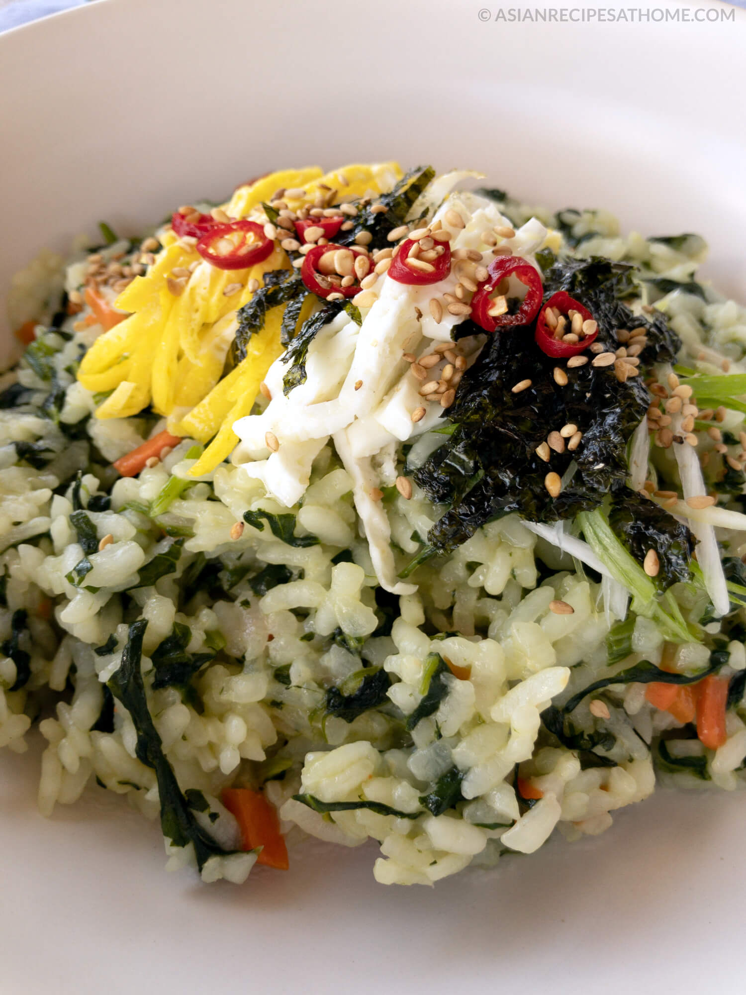 Korean spinach rice is served with pan-fried egg strips, strips of roasted seaweed, and topped with a drizzle of our savory Sesame Green Onion sauce.
