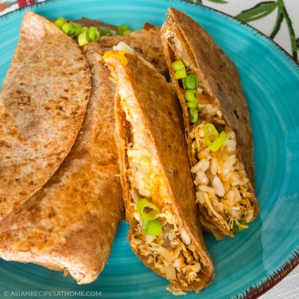 Delicious kimchi fried rice, chicken, cheese, tomatoes, and onions are packaged nicely in a browned tortilla.