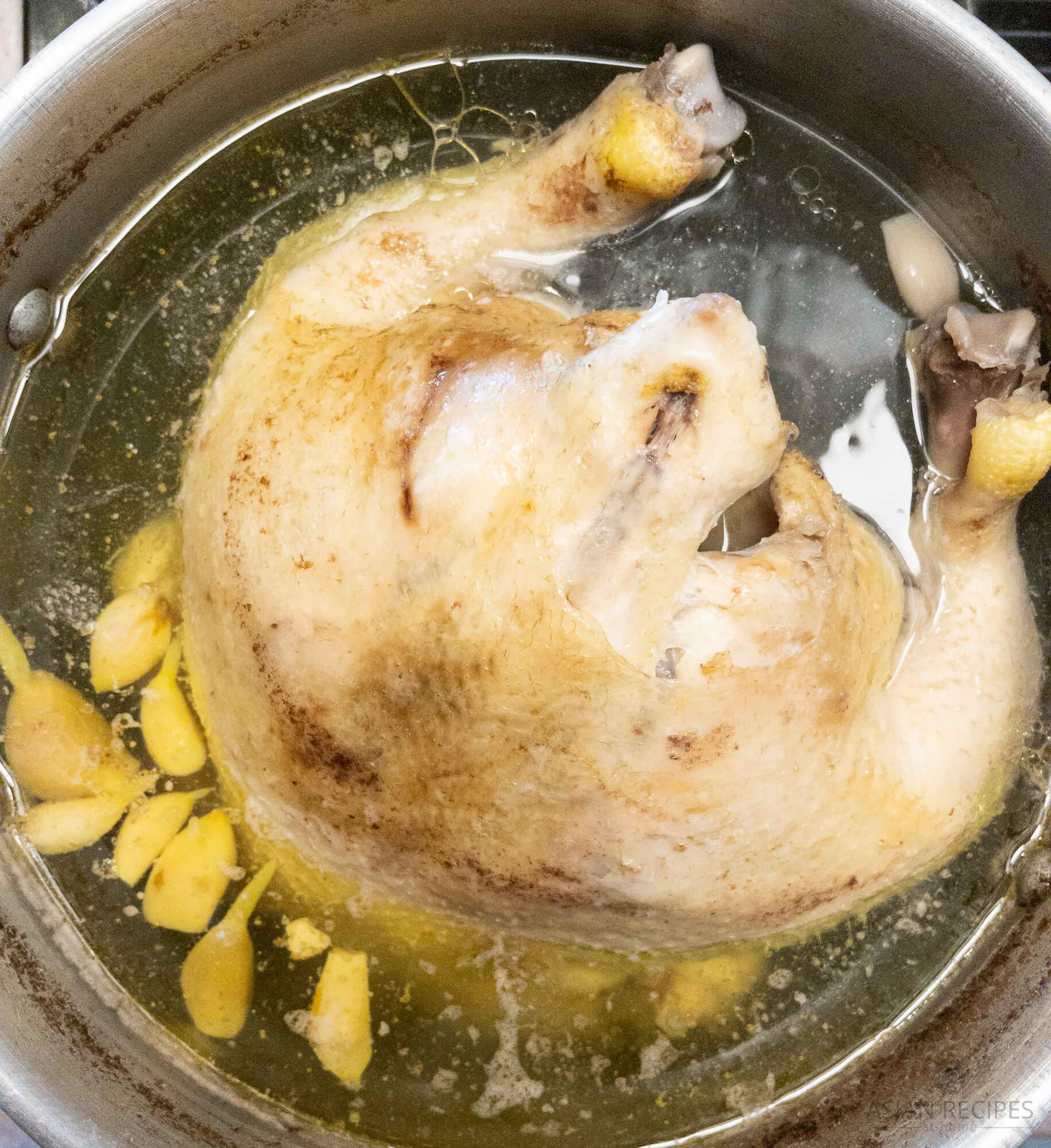 Chicken boiling in pot with reduction in water.